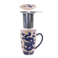 Decorative mug with dragon design, metal tea infuser, and lid on a white background