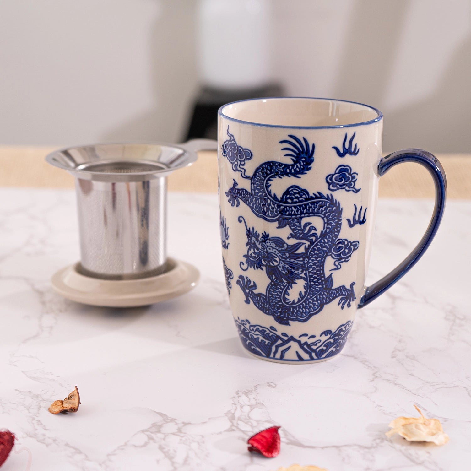White mug with blue dragon design on a marble surface with tea accessories.