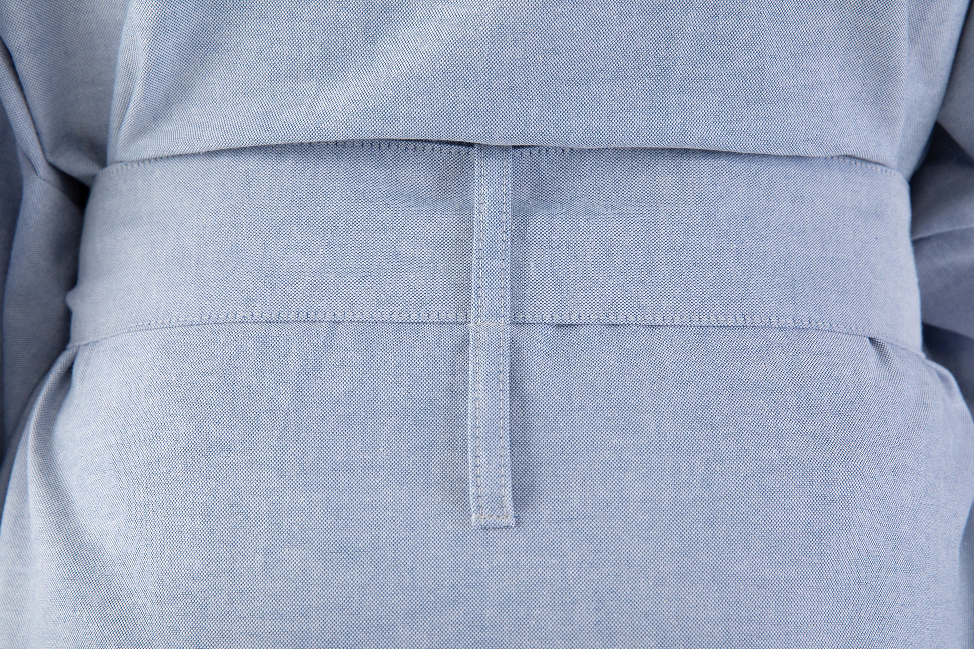 Close-up of a light blue garment with a belt and pocket detail.