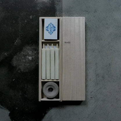 Set of candles in a wooden box with a decorative label on a dark background