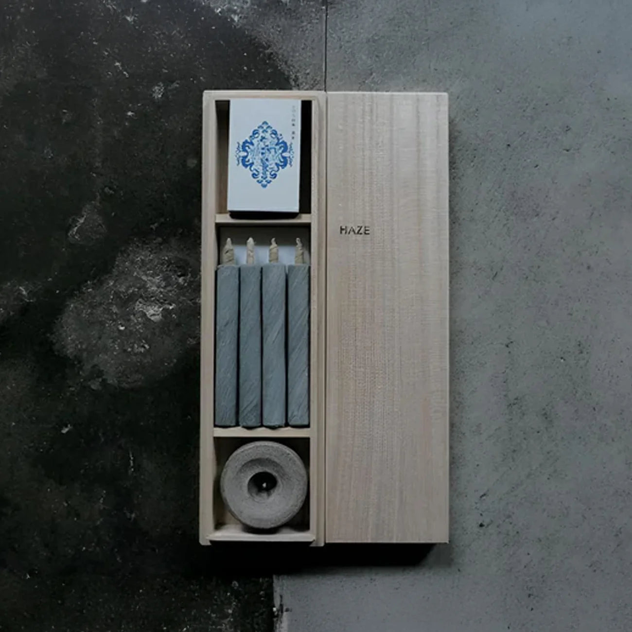 Wooden box with candles and a card on a textured surface