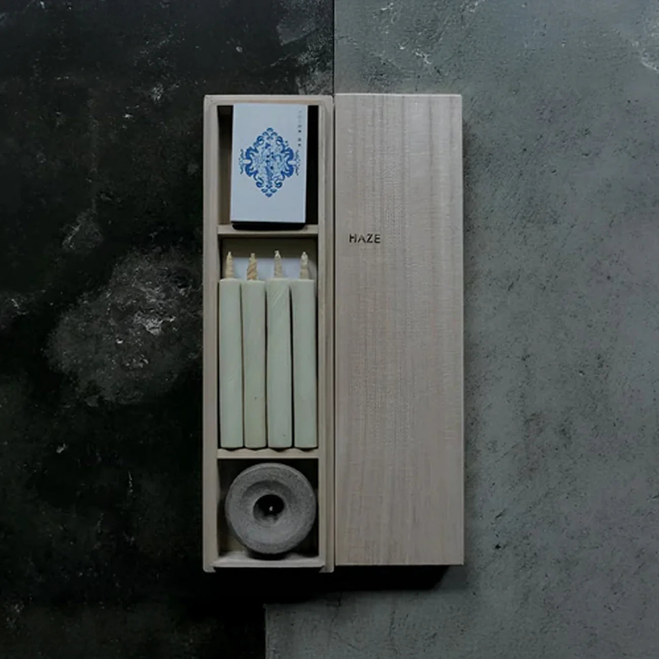 Set with candles and a holder on a dark surface