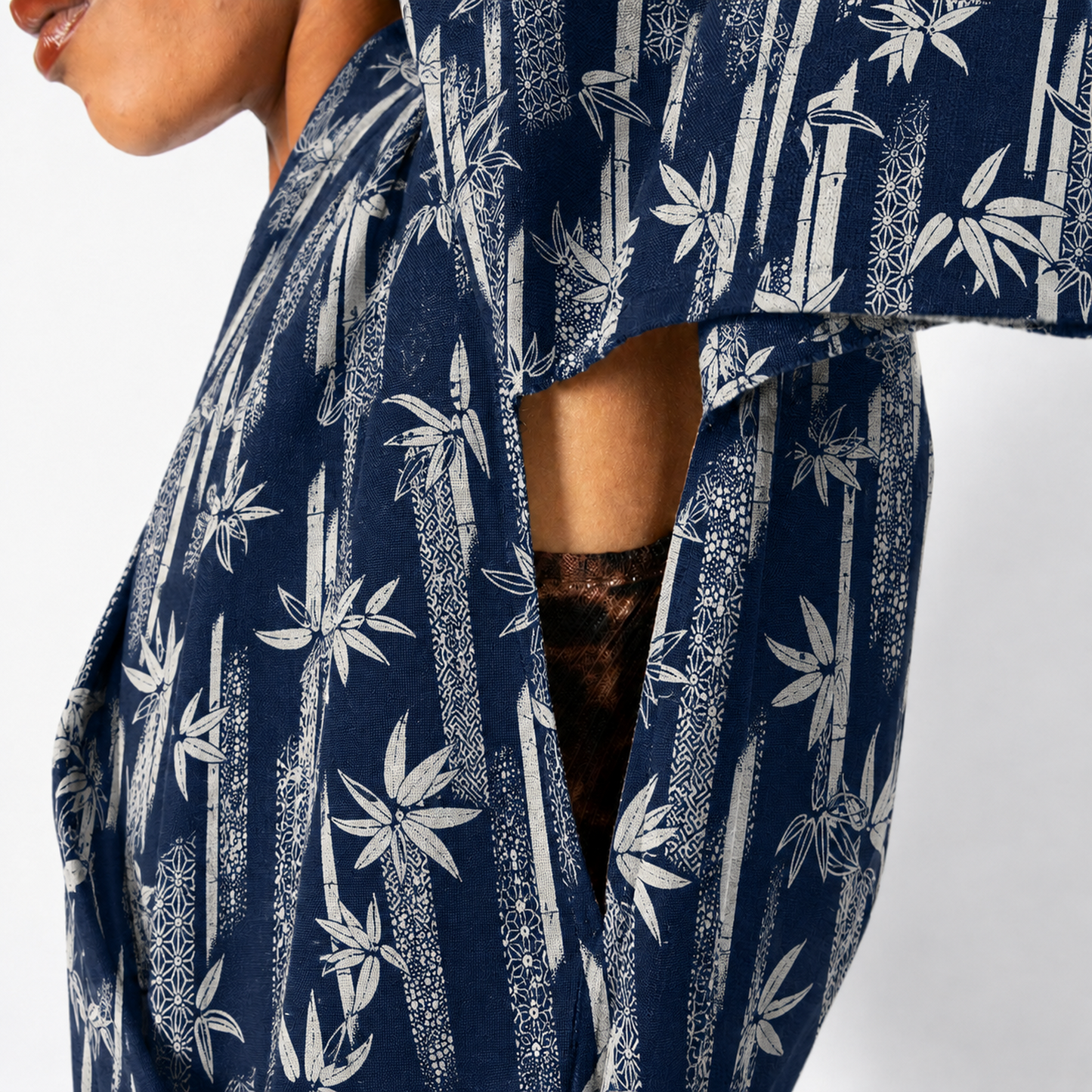 Close-up of a person wearing a navy blue kimono-style top with a white bamboo and leaf print, showing part of the chest, arm, and a dark brown lace insert.